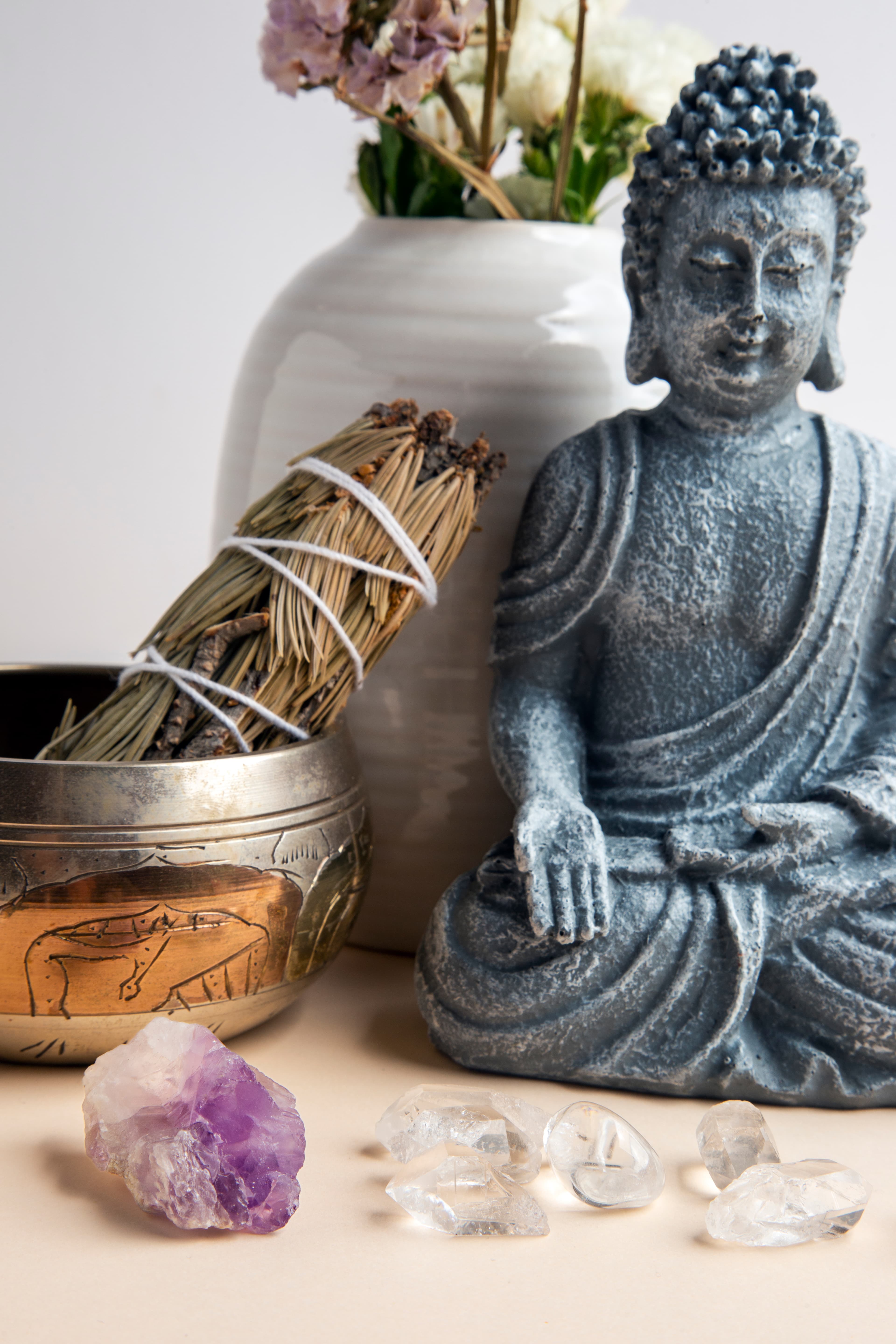 Meditation setup with Buddha statue, sage bundle, singing bowl, and crystals